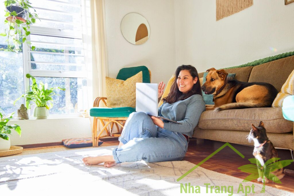 Woman relaxing with a dog and cat in a bright apartment living room.